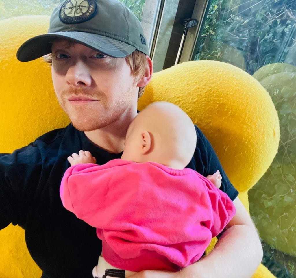 Rupert Grint says he's never watched all the Harry Potter movies and doesn't expect an invitation to TV series - Potterish Rupert Grint holds his daughter's lap, Wednesday