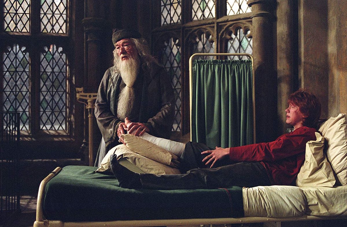 Alvo Dumbledore descansa sua mão na perna machucada de Rony Weasley